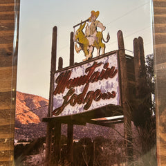 Decorative metal sign with text and figures on a wooden surface