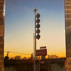 Vintage-style photo of a motel sign and windmill against a blue sky.