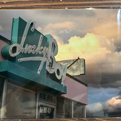 Vintage-style photo of a building with a sign reading 'Lucky Boy' against a cloudy sky.