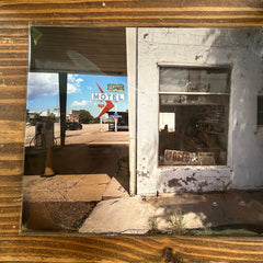 Rustic wooden wall with a framed photograph of a motel sign and old building.