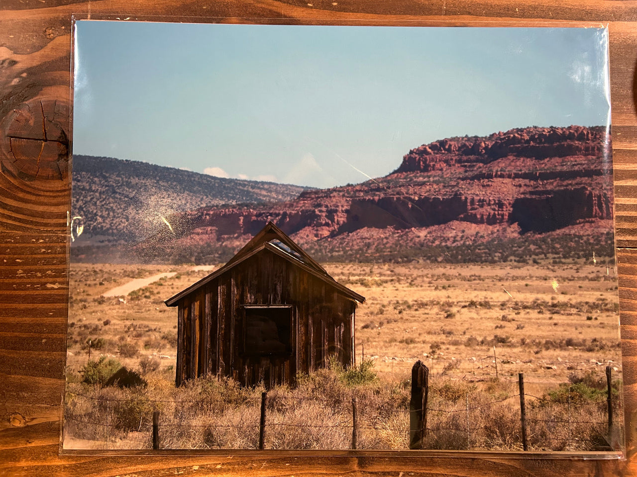 A scenic print of a desert landscape with a wooden cabin and mountains.