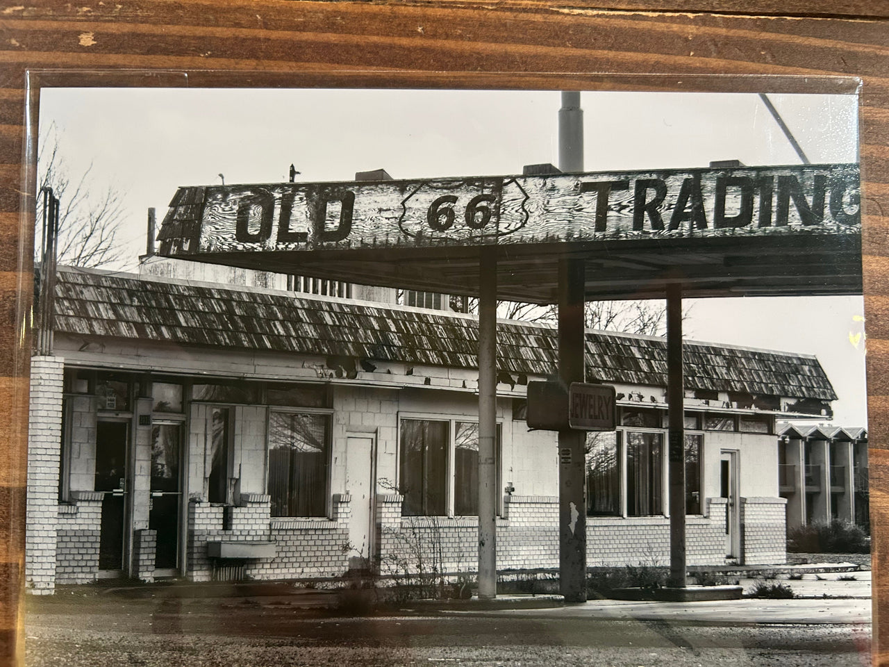 Black and white photo of a building with 'Old 66 Trading' sign on a wooden frame.