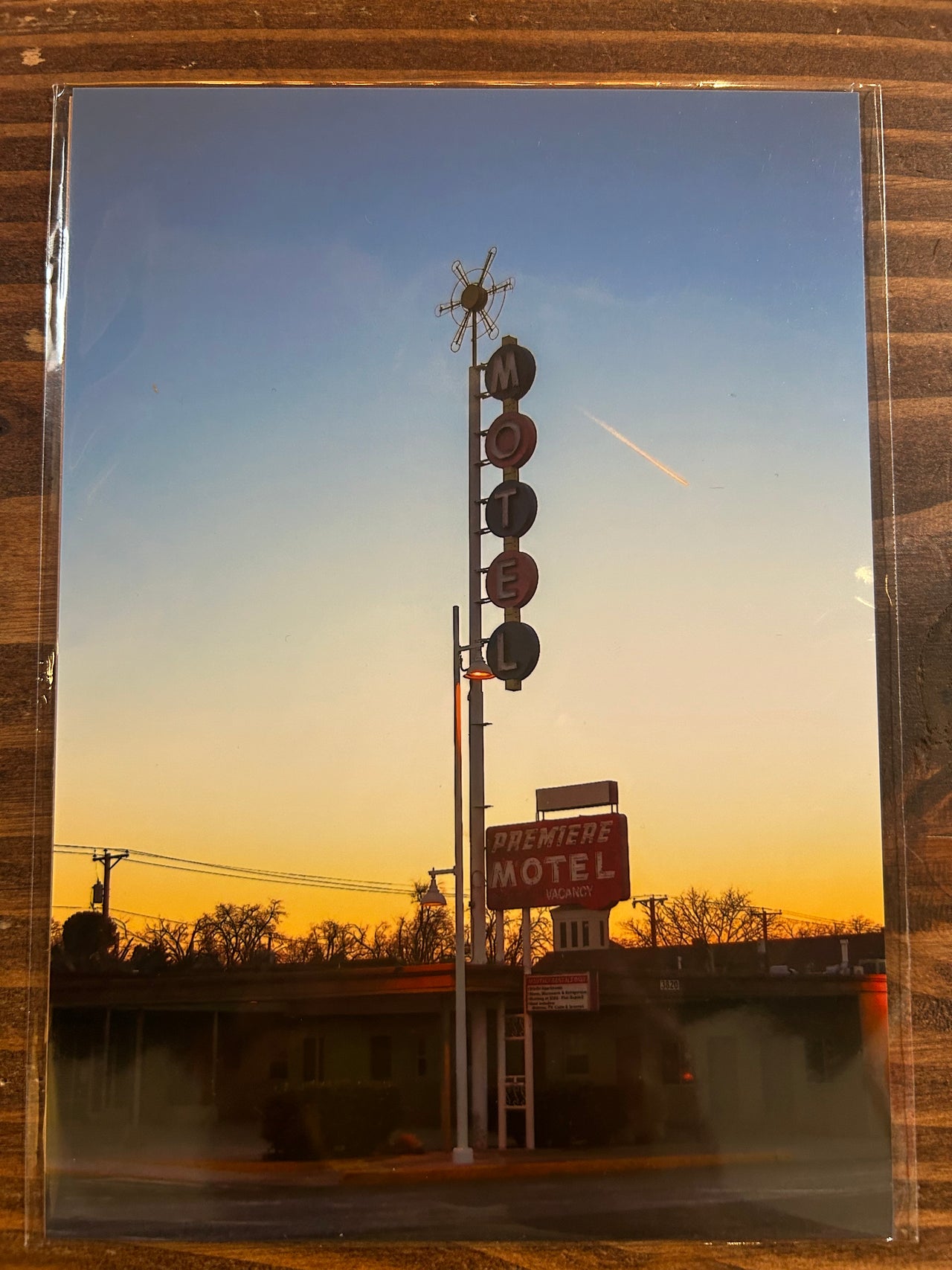 Vintage-style photo of a motel sign and windmill against a blue sky.