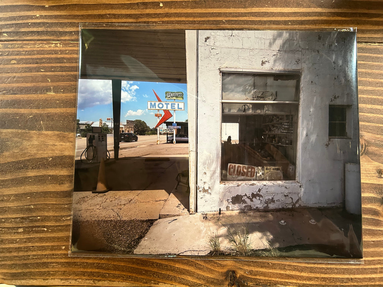 Rustic wooden wall with a framed photograph of a motel sign and old building.